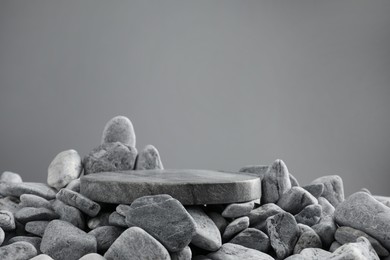 Photo of Presentation for product. Stone and pebbles on grey background. Space for text