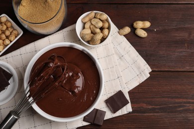 Photo of Bowl of chocolate cream with whisk and nuts on wooden table, flat lay. Space for text