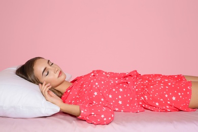 Photo of Beautiful teen girl sleeping with comfortable pillow on bed against color background. Space for text