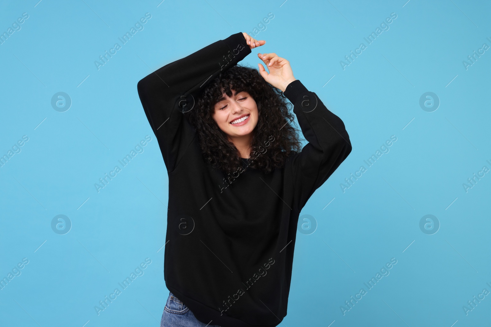 Photo of Happy young woman in stylish black sweater on light blue background