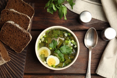 Photo of Delicious sorrel soup with eggs served on wooden table, flat lay
