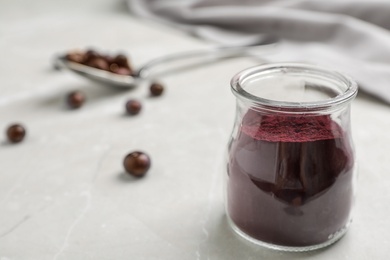 Photo of Jar with acai powder on gray table