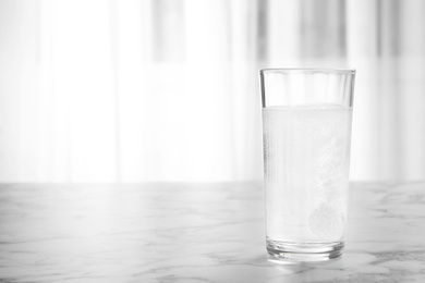 Photo of Glass of water with effervescent tablet on marble table indoors, space for text