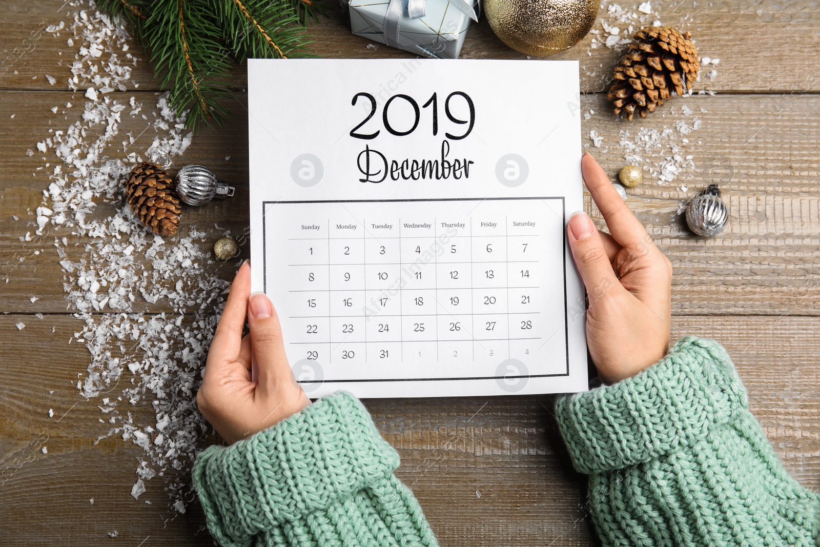 Photo of Woman with paper calendar at wooden table, top view