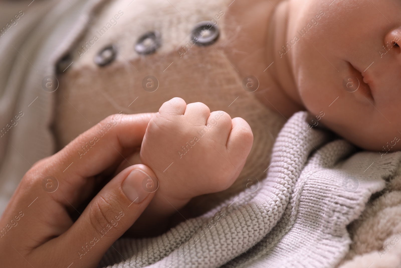 Photo of Mother and her newborn baby on beige crocheted plaid, closeup