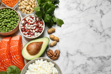 Products rich in protein on white marble table, flat lay. Space for text