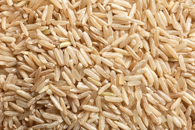 Photo of Raw brown rice as background, closeup view