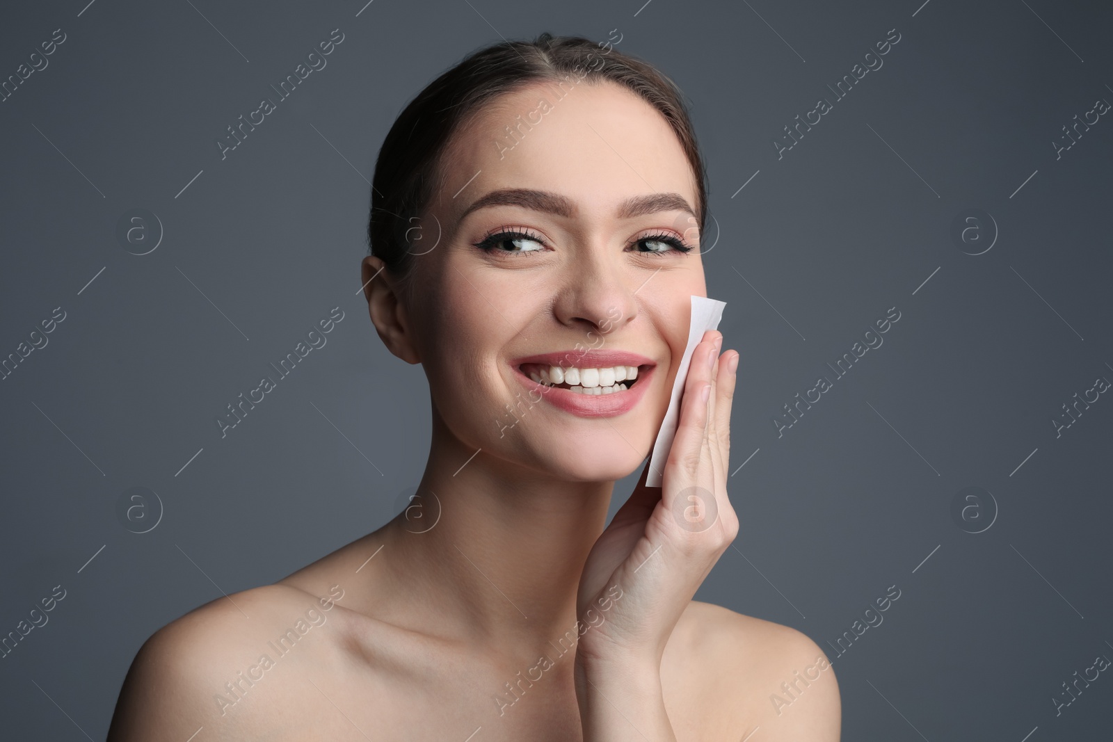 Photo of Beautiful woman using mattifying wipe on grey background