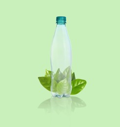 Image of Bottle made of biodegradable plastic and leaves on green background