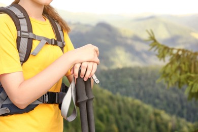 Photo of Woman with backpack and trekking poles hiking in mountains, closeup. Space for text
