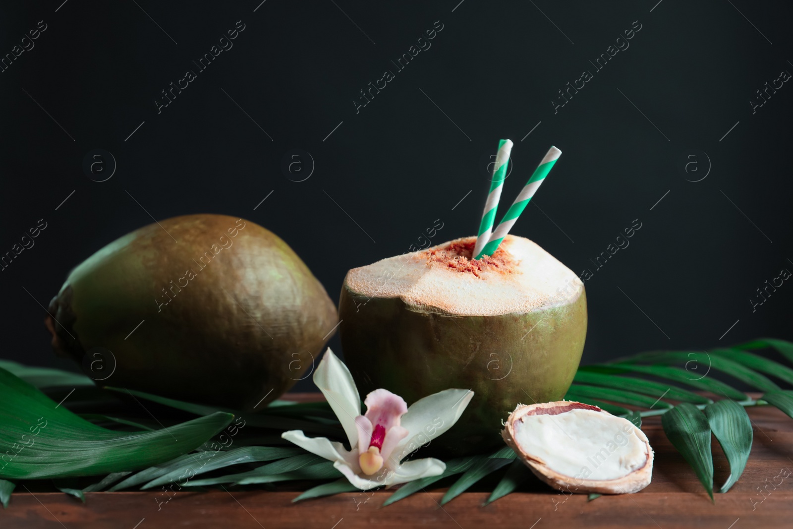 Photo of Beautiful composition with fresh green coconuts on table against dark background