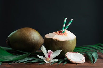 Photo of Beautiful composition with fresh green coconuts on table against dark background