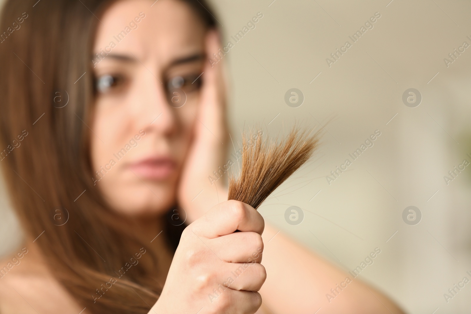 Photo of Emotional woman with damaged hair on blurred background, selective focus. Split ends