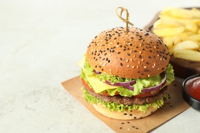 Photo of Burger with delicious patty and french fries on light table, closeup. Space for text