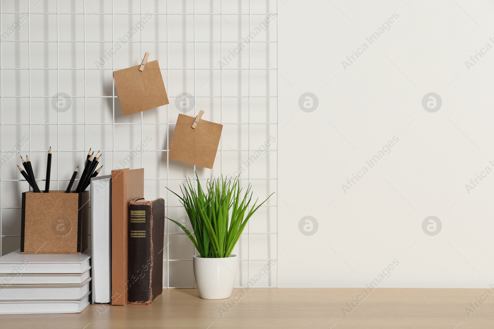 Photo of Comfortable workplace with wooden desk near white wall. Space for text