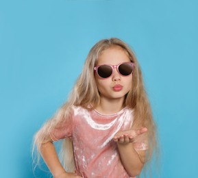 Photo of Girl in stylish sunglasses on light blue background
