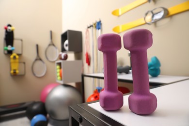 Pink dumbbells on white table in room with other sports equipment