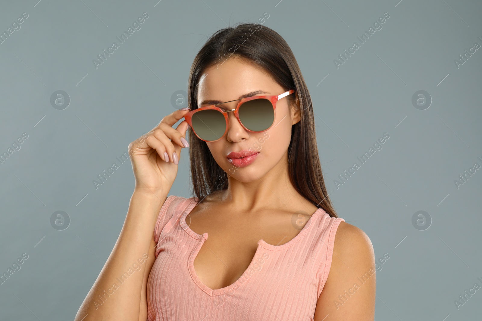 Photo of Beautiful young woman wearing sunglasses on grey background