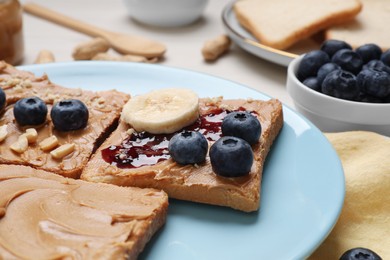 Different tasty toasts with nut butter and products on table, closeup