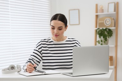 Photo of Online translation course. Student writing near laptop at home