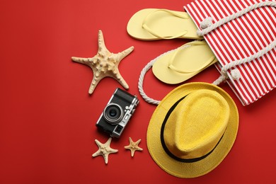 Stylish bag with beach accessories on red background, flat lay