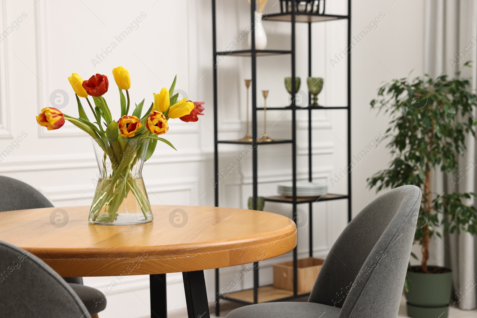 Photo of Stylish dining room interior with comfortable furniture and beautiful tulips