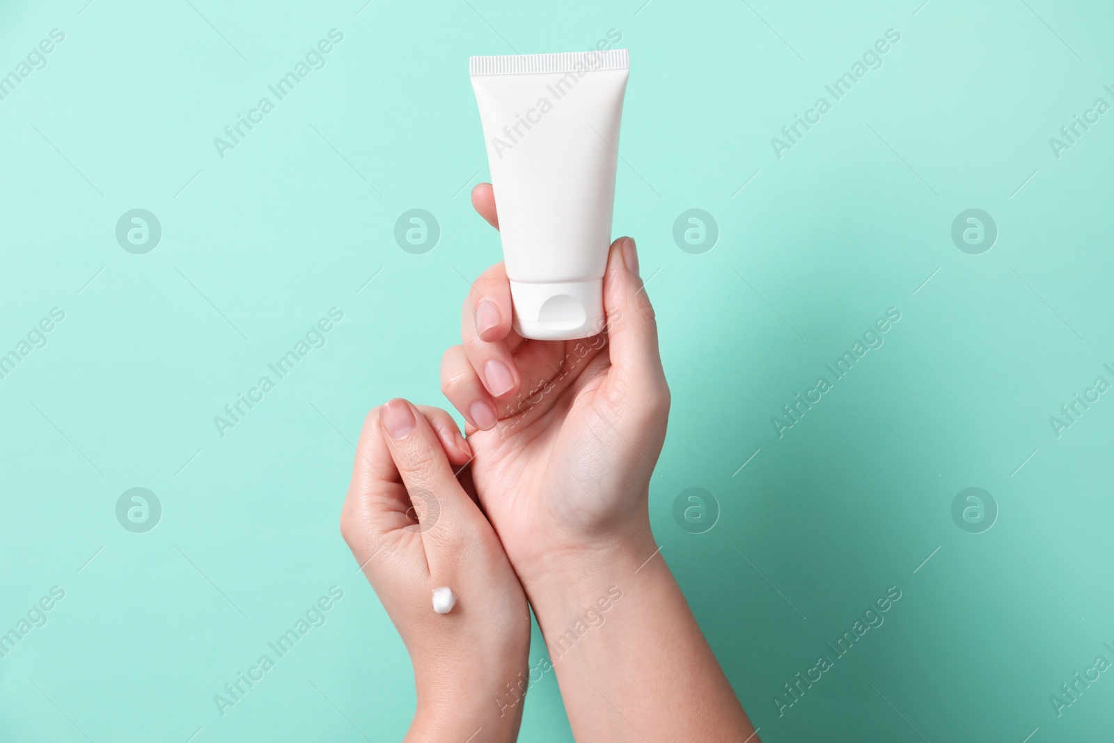 Photo of Woman with tube of hand cream on turquoise background, closeup