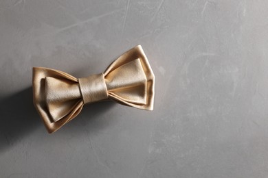 Photo of Stylish pale yellow bow tie on gray textured background, top view. Space for text