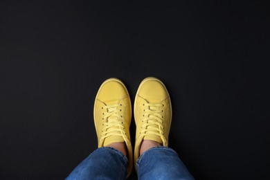 Photo of Woman in stylish sneakers on black background, top view