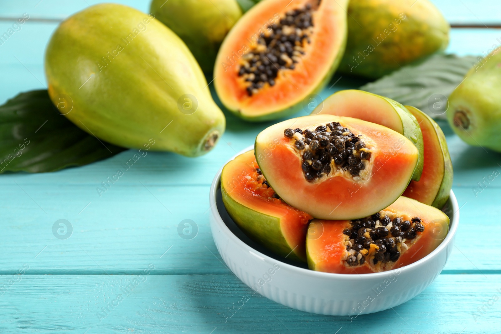 Photo of Fresh ripe papaya fruits on turquoise wooden table