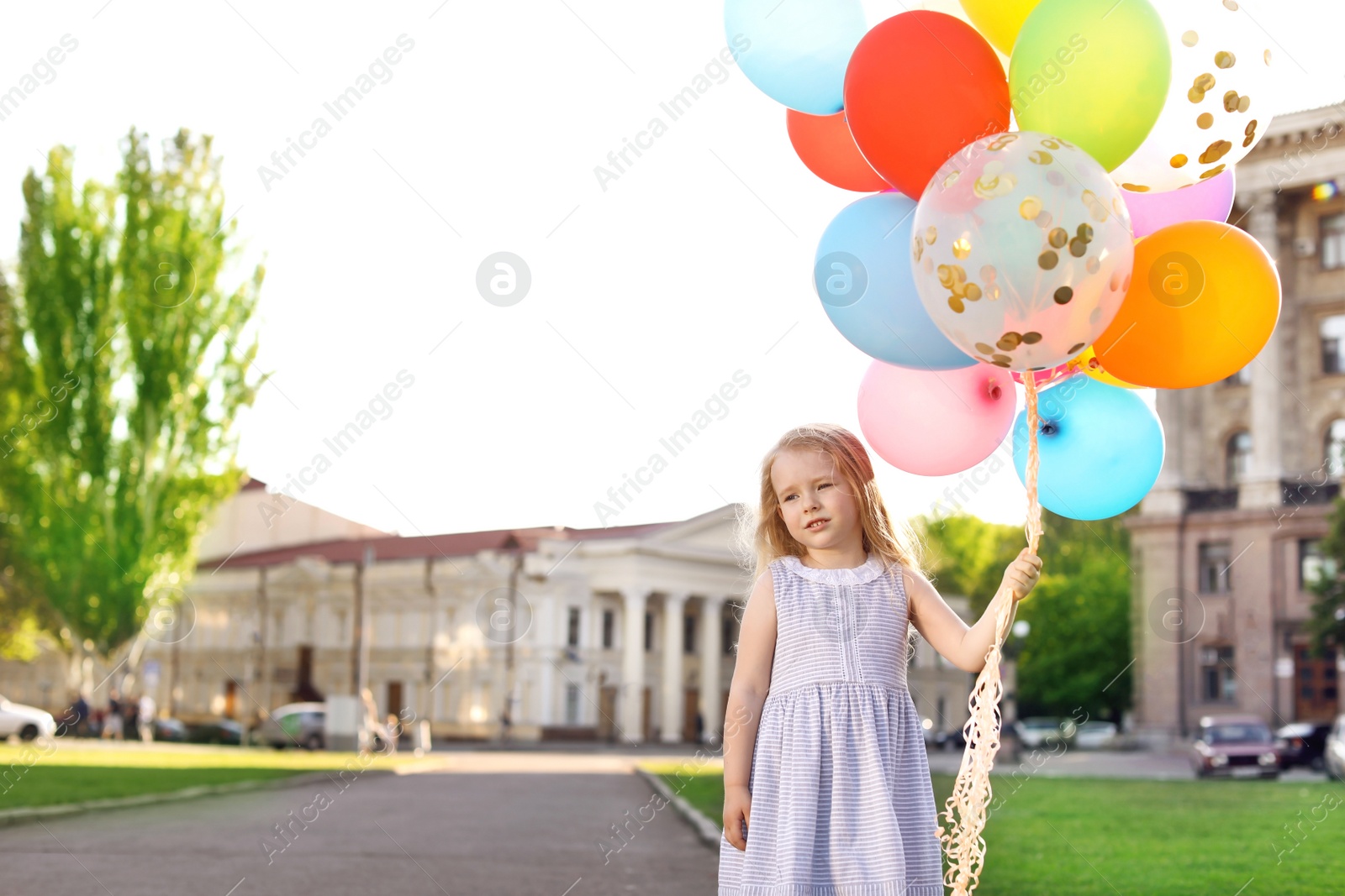 Photo of Cute little girl with colorful balloons outdoors on sunny day