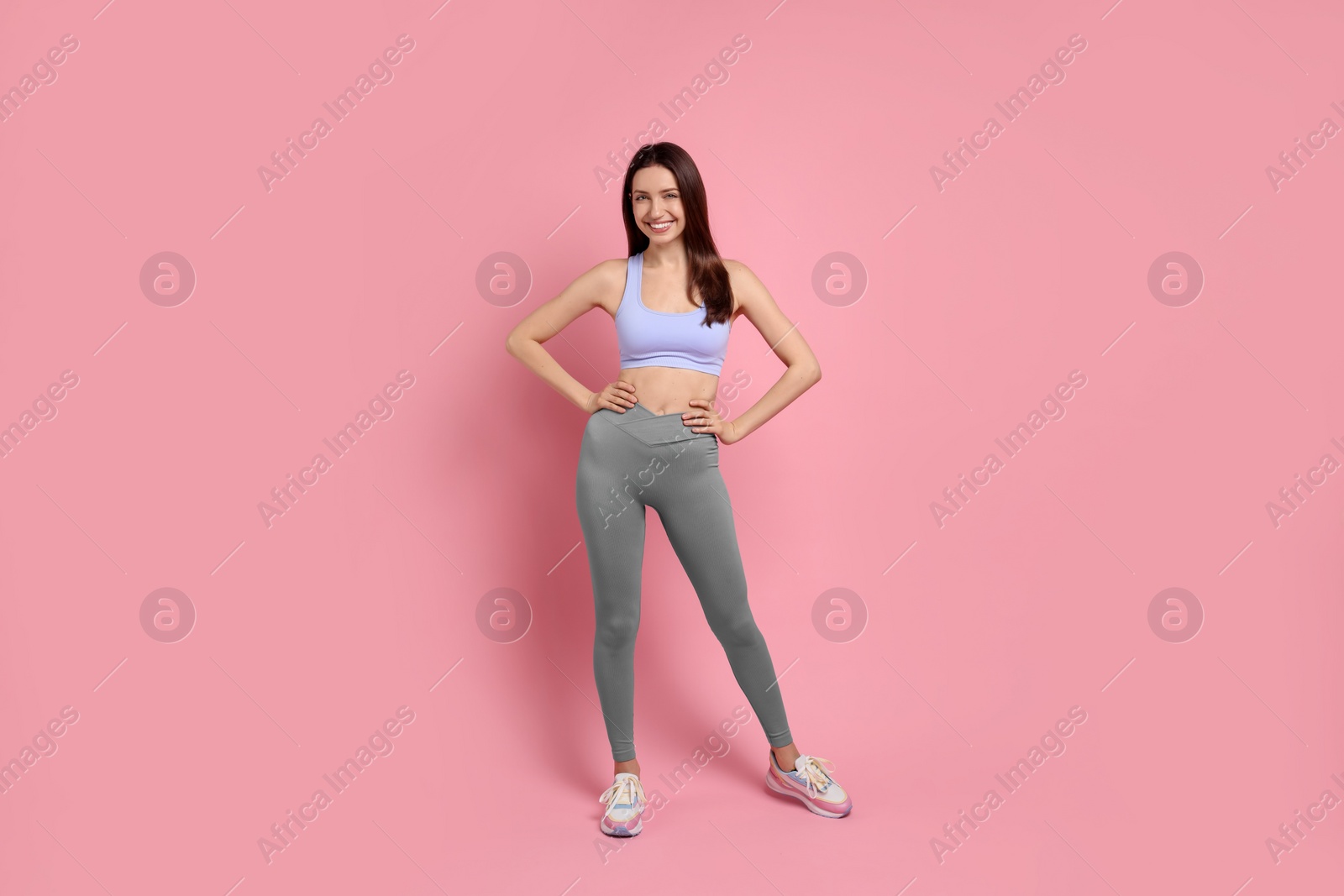 Photo of Happy young woman with slim body posing on pink background