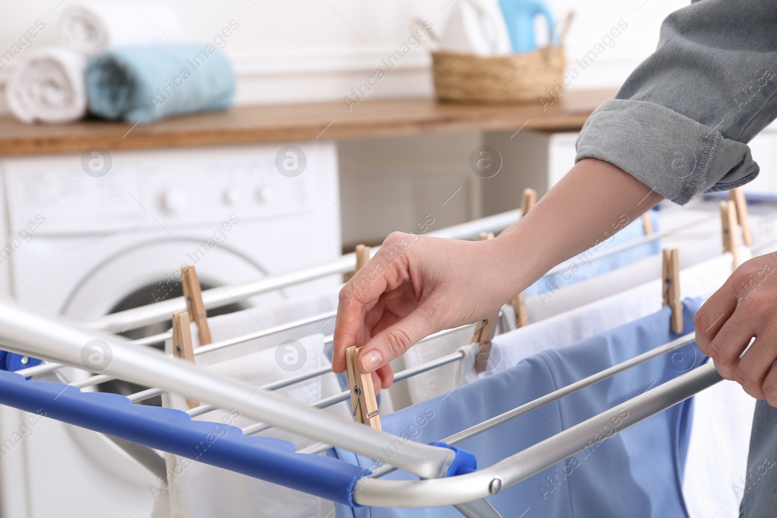 Photo of Woman hanging clean laundry on drying rack in bathroom, closeup