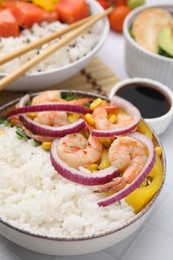 Delicious poke bowl with shrimps, rice and vegetables on white table, closeup