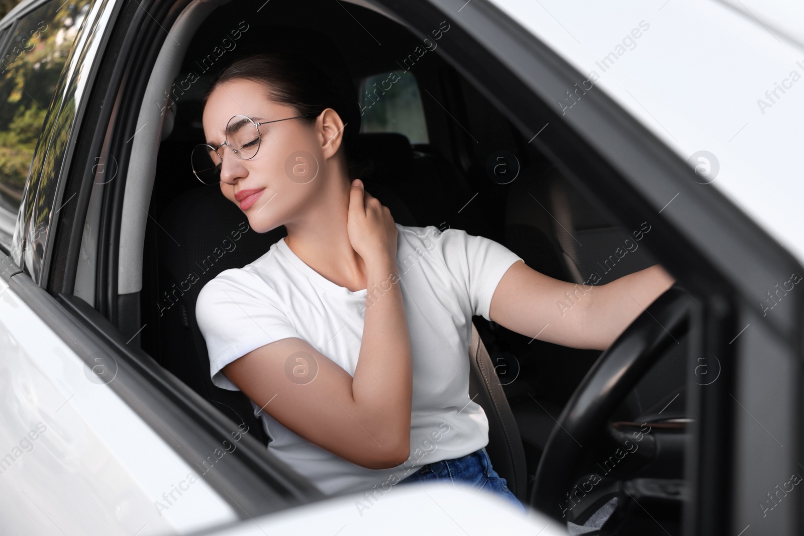 Photo of Young woman suffering from neck pain in her car