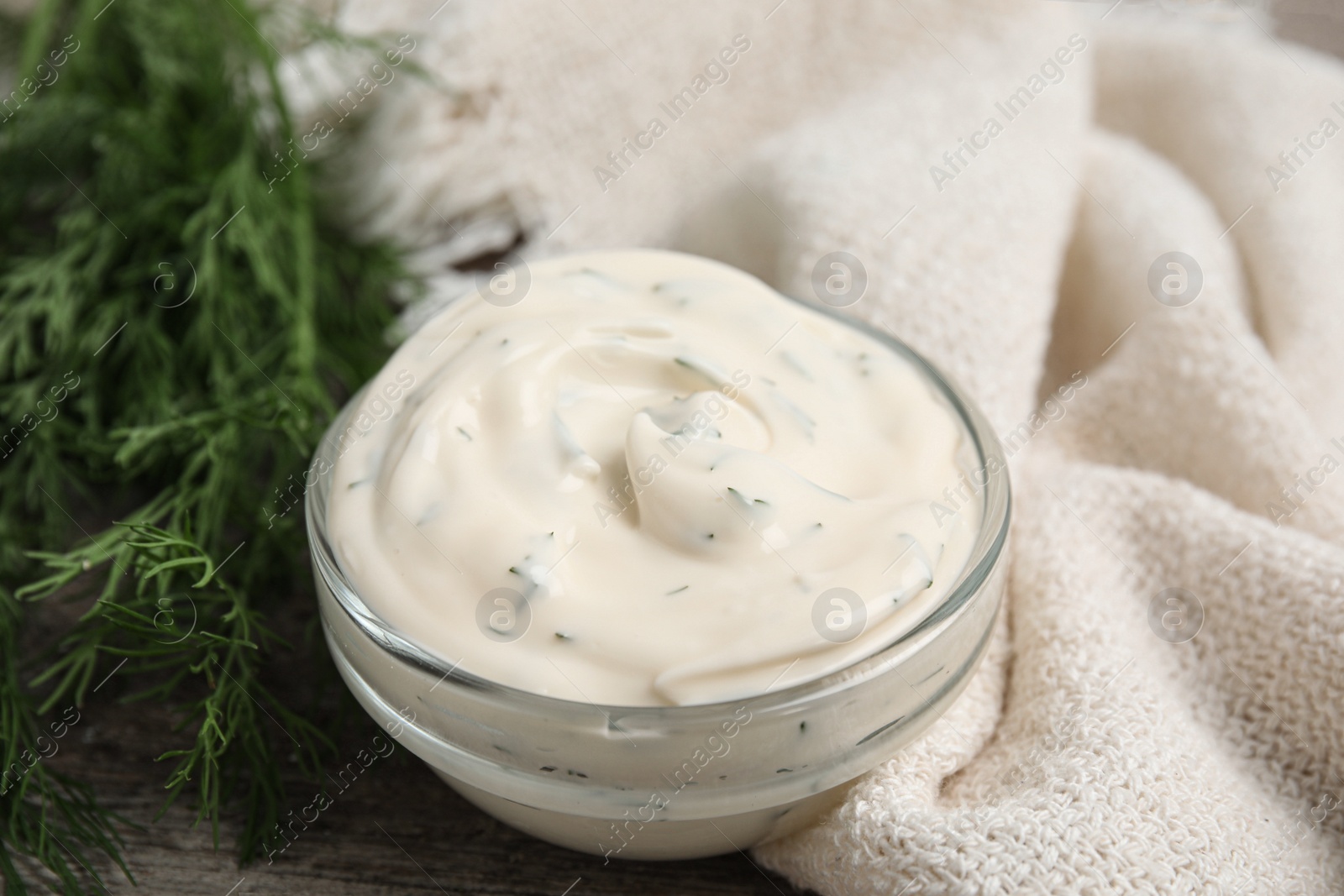 Photo of Tasty creamy sauce and fresh dill on wooden table, closeup