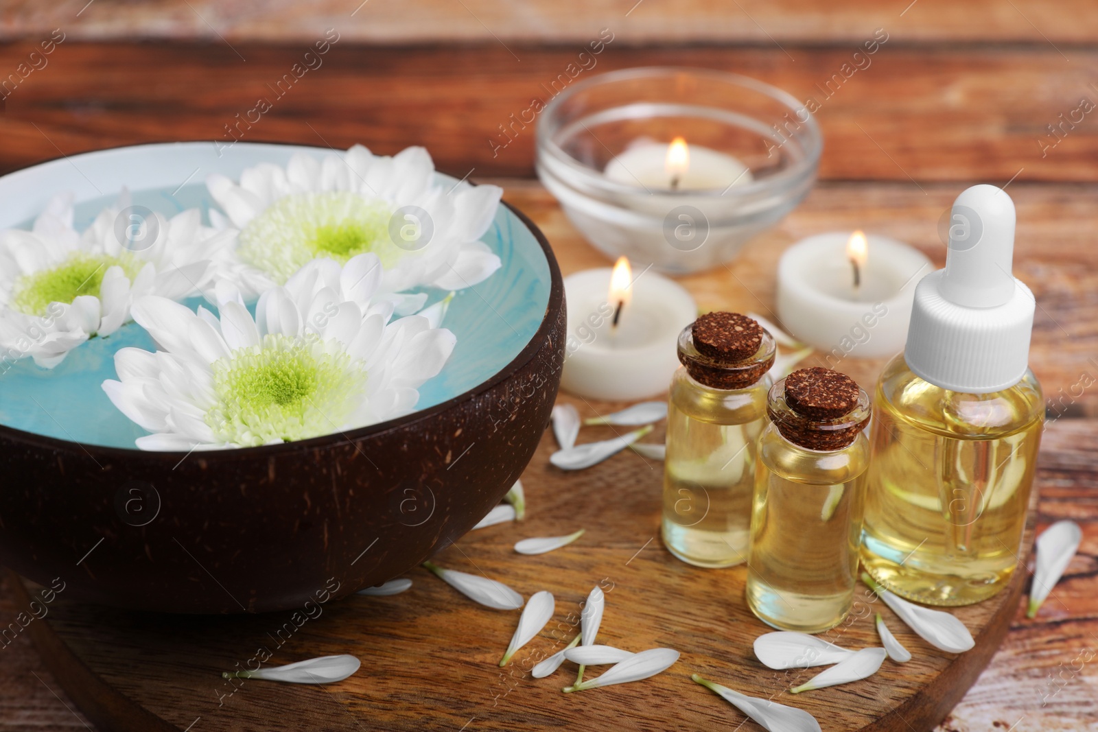 Photo of Beautiful composition with bowl of water, flowers and essential oils on table, closeup. Spa treatment