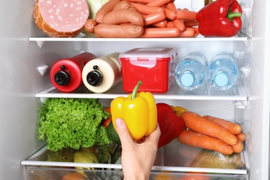 Photo of Woman taking bell pepper from refrigerator, closeup