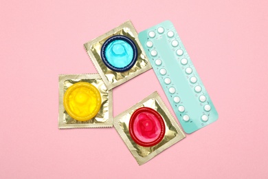 Photo of Condoms and birth control pills on pink background, top view. Safe sex