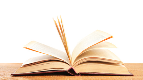 Open book on wooden table against white background