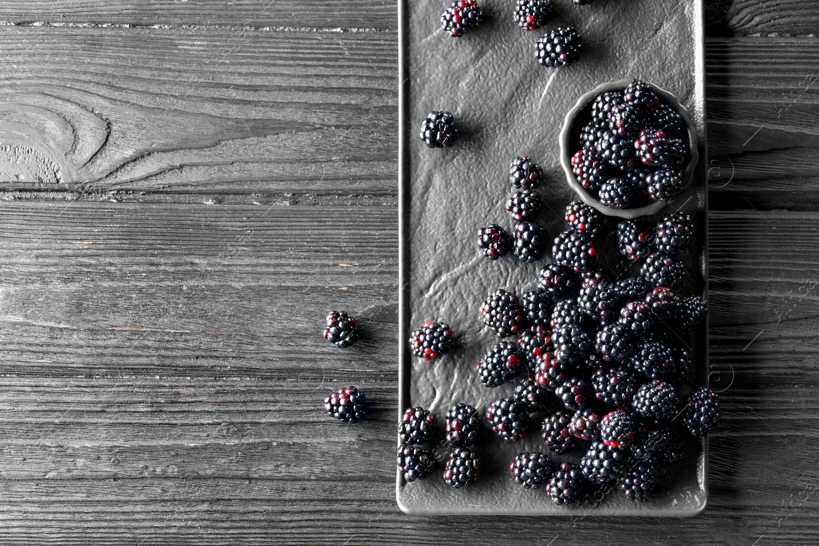 Photo of Fresh ripe blackberries on black wooden table, flat lay. Space for text