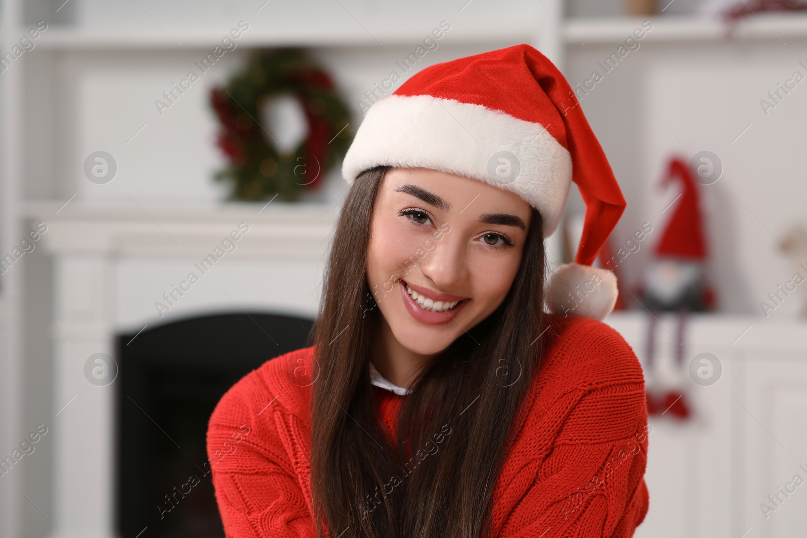 Photo of Portrait of smiling woman wearing red Christmas hat indoors