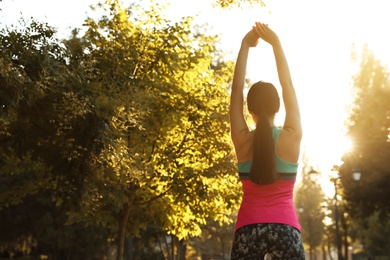 Photo of Young woman stretching before morning run in park, back view. Space for text