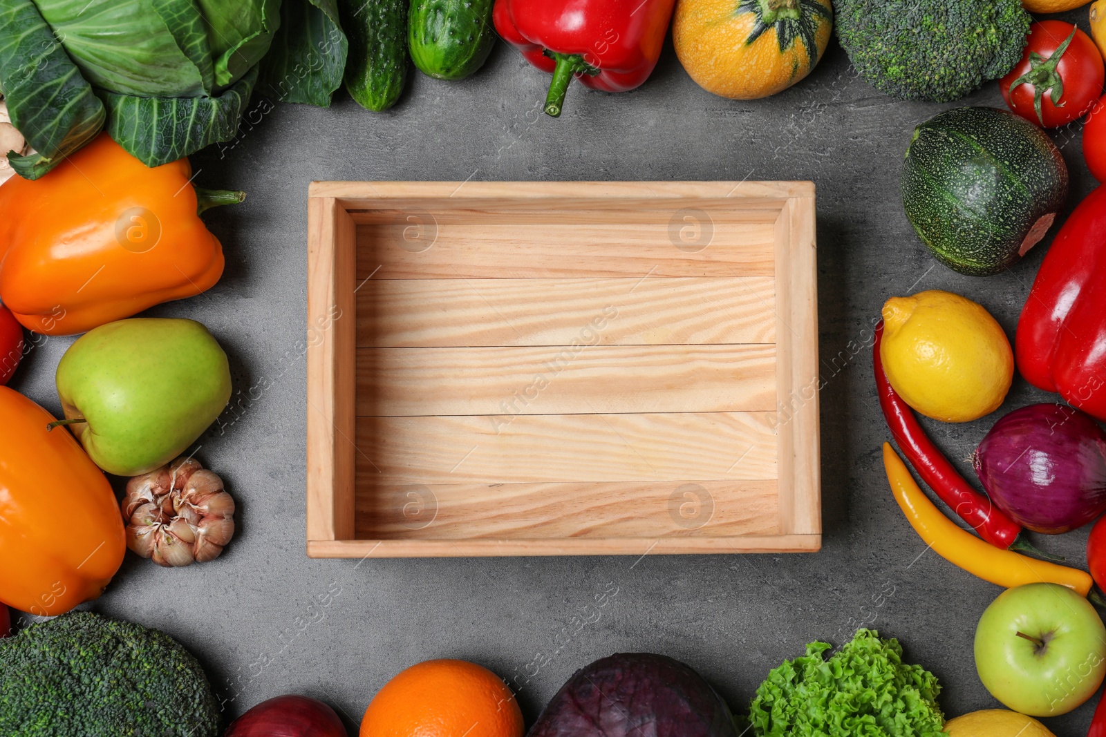 Photo of Different fresh vegetables around empty wooden crate on table, flat lay