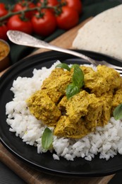 Photo of Delicious rice and chicken with curry sauce on wooden board, closeup