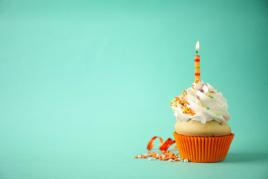 Photo of Delicious birthday cupcake with candle on light green background. Space for text