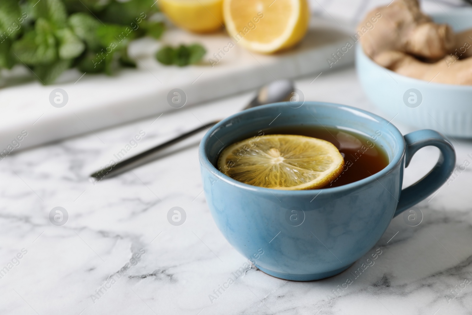 Photo of Cup of hot tea with lemon on marble table, space for text. Cough remedy