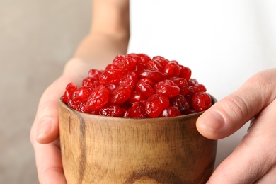 Woman holding bowl with tasty cherries on color background, closeup. Dried fruits as healthy food