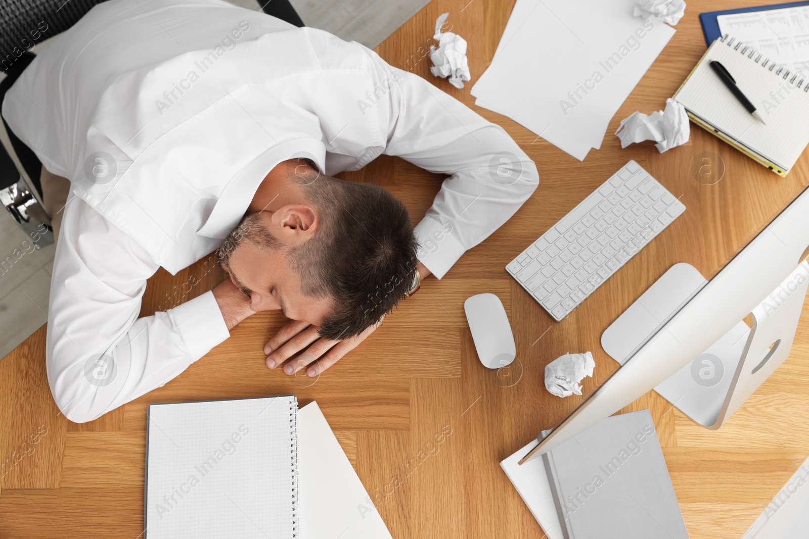 Photo of Tired man sleeping at workplace, top view