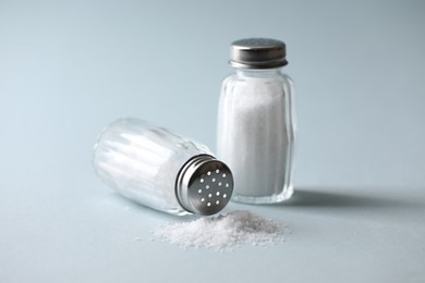 Photo of Natural salt in shakers on color background